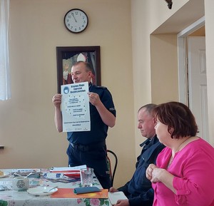 Policjant trzymający plakat dot. Krajowej Mapy Zagrożeń Bezpieczeństwa