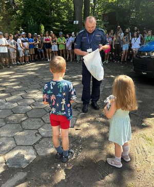 Policjant wręczający uczestnikom obozu drobne upominki.