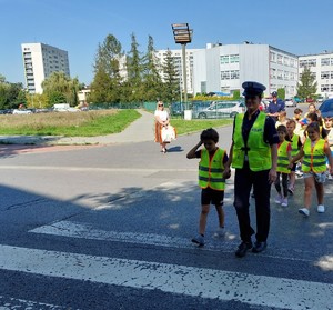 Policjantka wydziału ruchu drogowego przeprowadzająca dzieci przez przejście dla pieszych