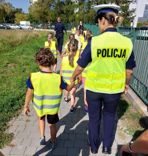 Policjanci idący z grupą dzieci.