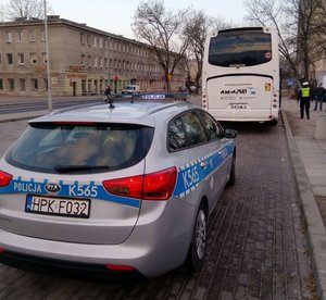 Na pierwszym planie radiowóz, na drugim planie policjant i kontrolowany autobus