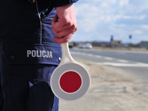Policjant trzymający w dłoni tarczę do zatrzymywania pojazdów.