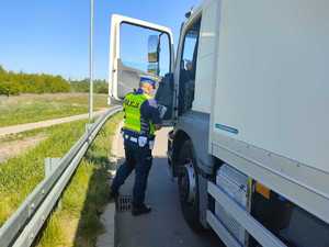 Policjant przeprowadzający kontrolę pojazdu ciężarowego.